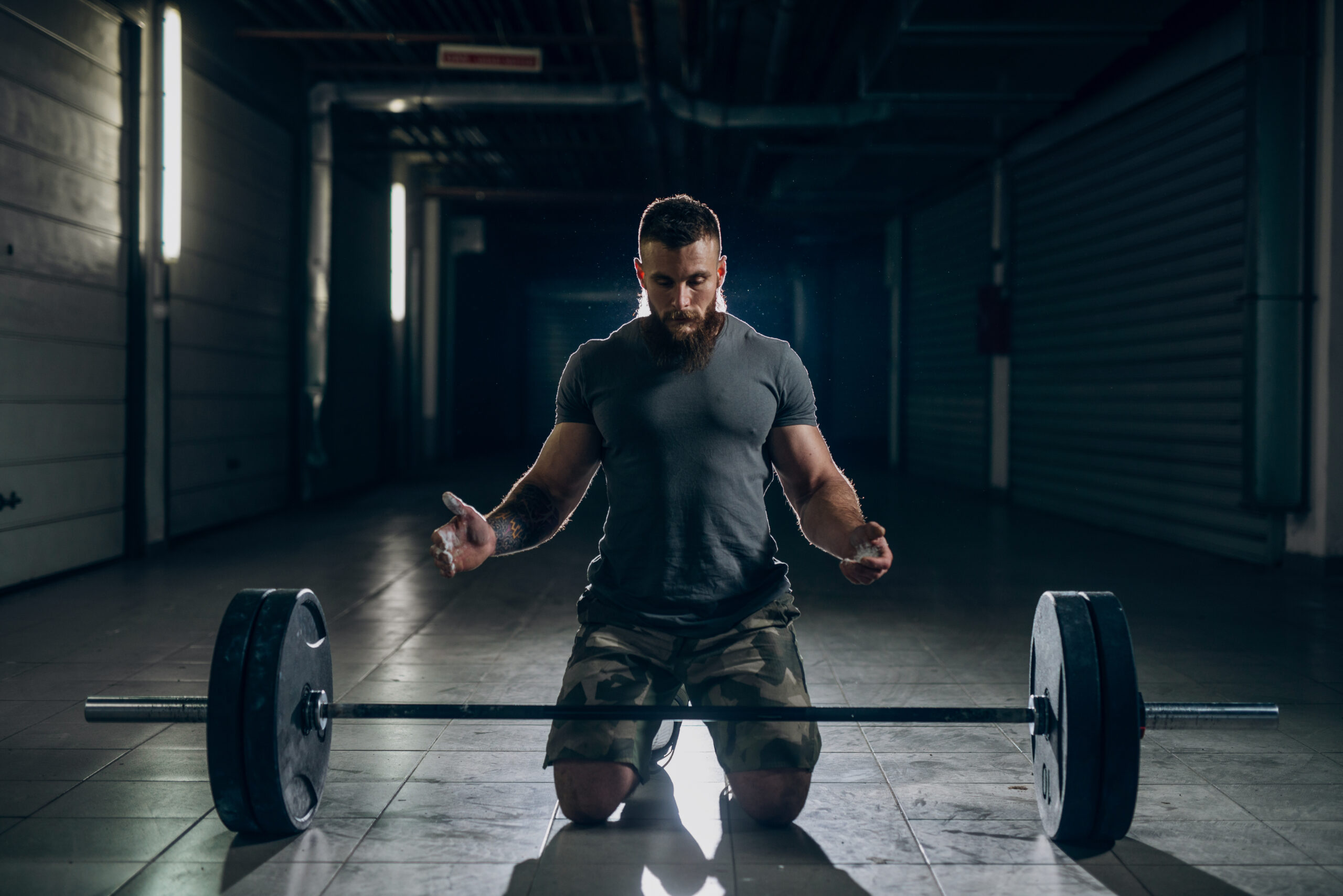 Muscular attractive caucasian bearded man kneeling with chalk po